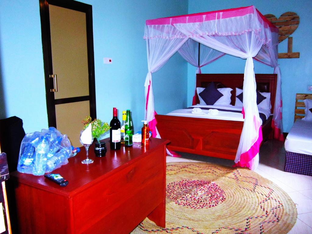 1 dormitorio con cama con dosel y mesa con botellas de vino en Safari Park House, en Arusha
