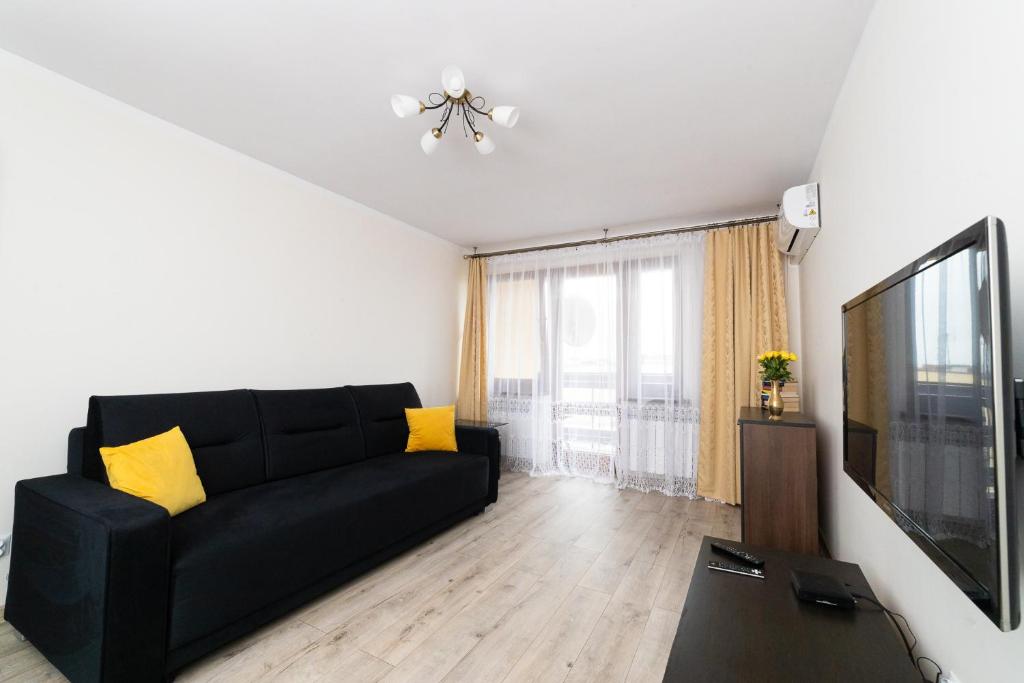 a living room with a black couch and a flat screen tv at Apartament Na Bajkowej in Busko-Zdrój