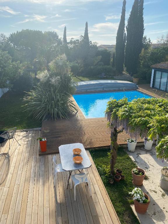 une terrasse en bois avec une table et une piscine dans l'établissement La villa de Michèle, à Marseillan