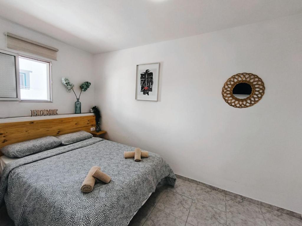 1 dormitorio con 1 cama y 2 zapatillas de madera en Apartamento OCEAN PEARL, en Corralejo