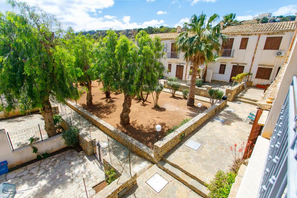 einen Blick über einen Innenhof mit Bäumen und einem Gebäude in der Unterkunft SanVitoTour- Residence Il Baglio in San Vito lo Capo