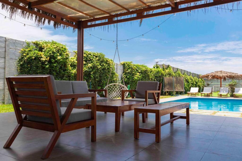 un patio con tavolo, sedie e piscina di SOLARIUM CHINCHA Casa de Campo y Playa de 1000mts! a Sunampe