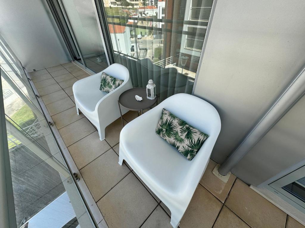 two white chairs and a table in a room with windows at Apartamento Lux 1882 in Figueira da Foz