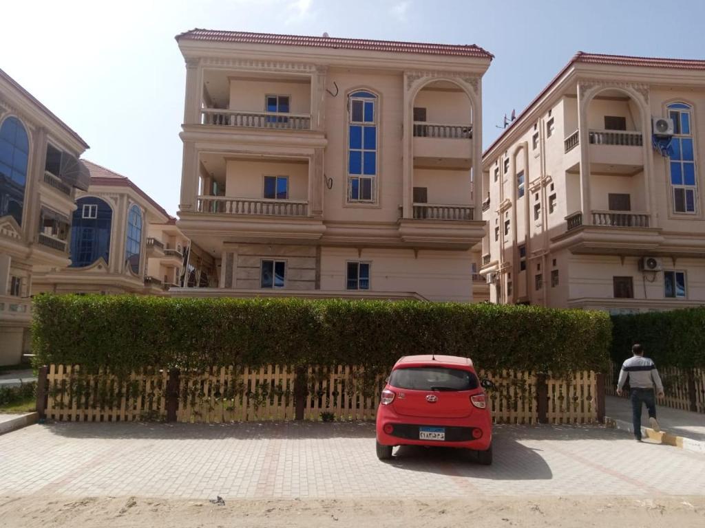 een kleine rode auto geparkeerd voor een gebouw bij راس البر in Ras El Bar