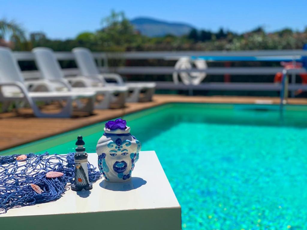 a blue and white vase sitting next to a swimming pool at Casa Contrada Molinello in Castellammare del Golfo