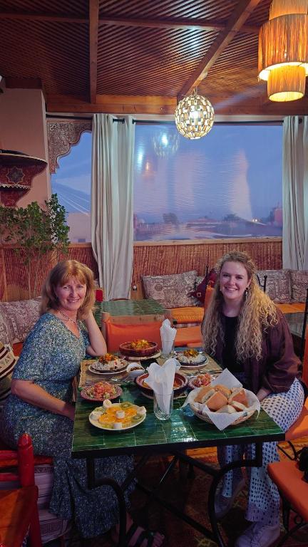 dos mujeres sentadas en una mesa con platos de comida en Riad Zahri, en Marrakech