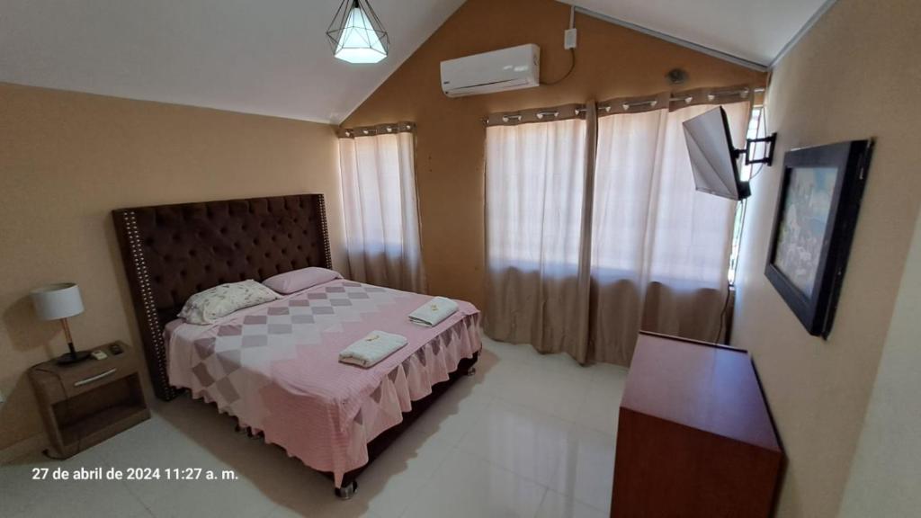 1 dormitorio con 1 cama con colcha rosa en Hotel House Hoskins Talara- con AIRE ACONDICIONADO, uso de cocina en Talara