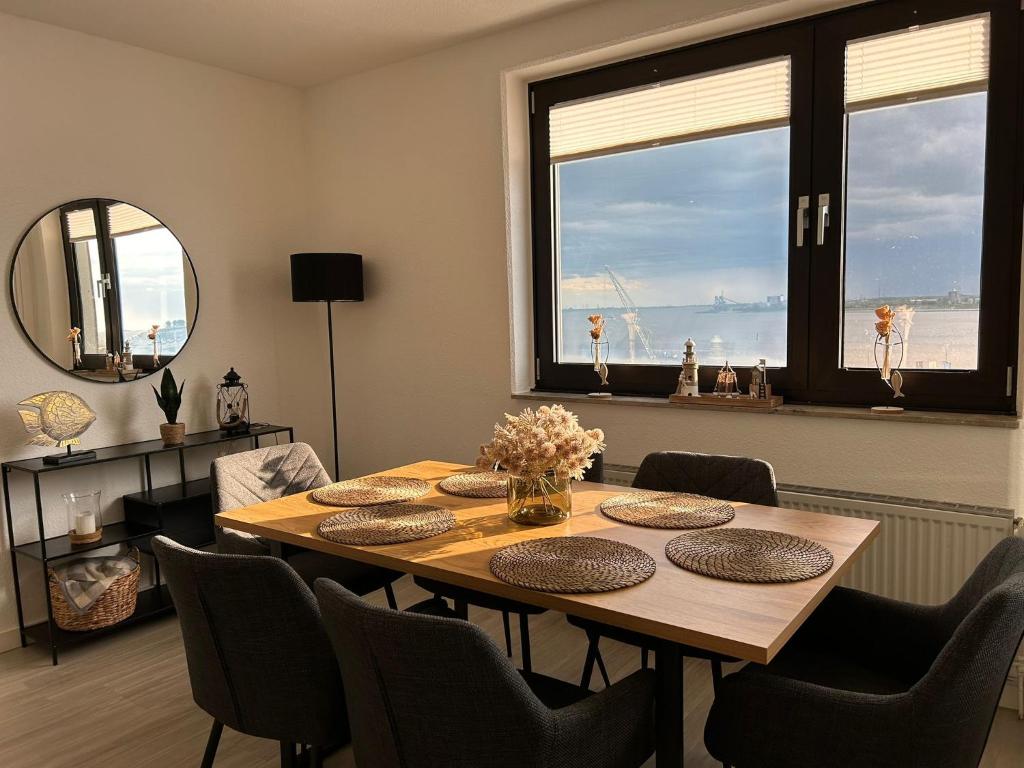 Un comedor con mesa y sillas de madera. en Gemütliche Ferienwohnung im Stadtzentrum mit wundervollem Blick, en Bremerhaven