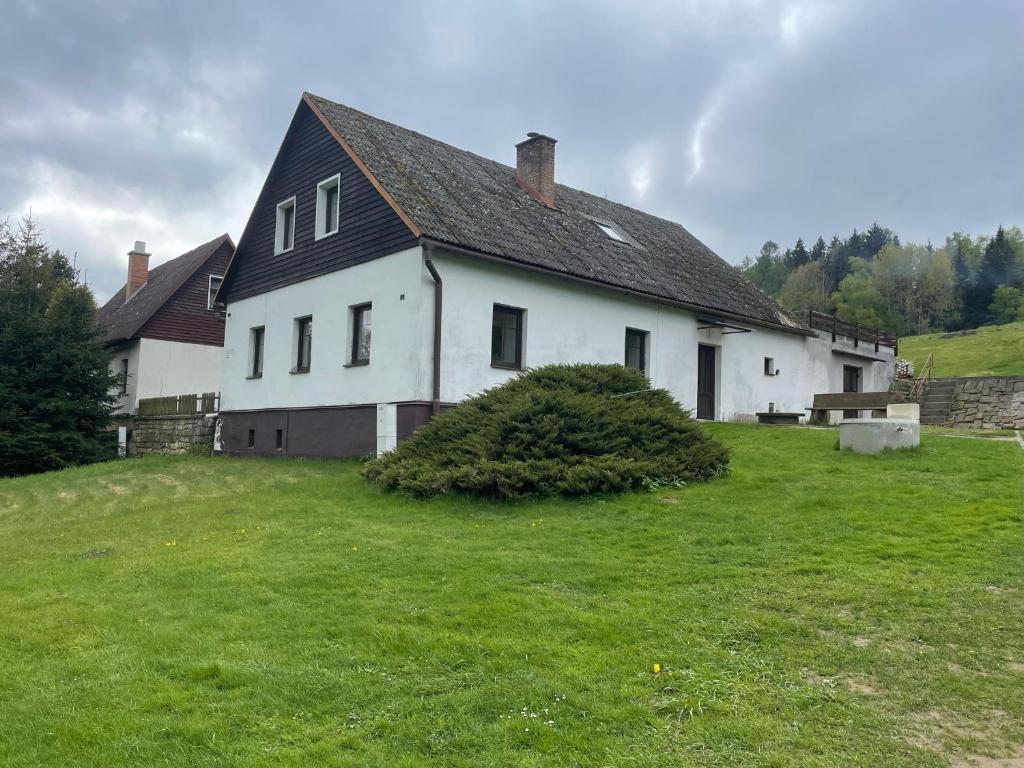 a white house with a black roof on a green field at Chata Svojáč in Svojanov