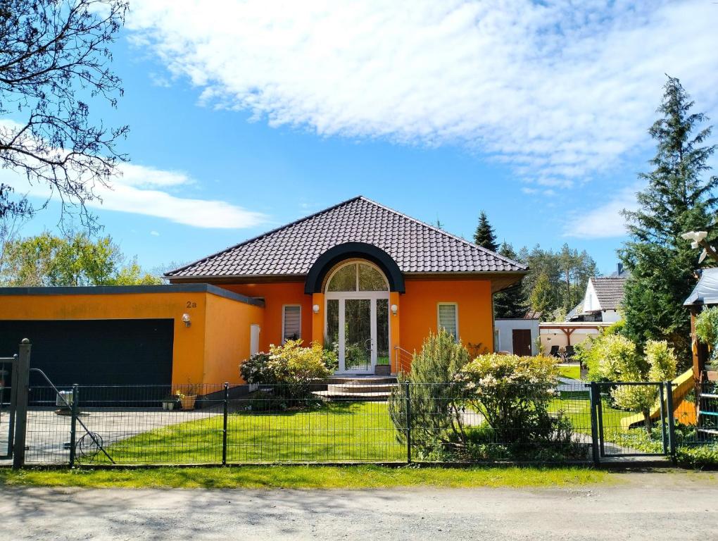 a orange house with a fence at Ferienwohnung Am Waldesrand - Garten, Terrasse, Grill, Luftkühler, Massagesessel, Kinderspielecke, Spielekonsole in Cottbus