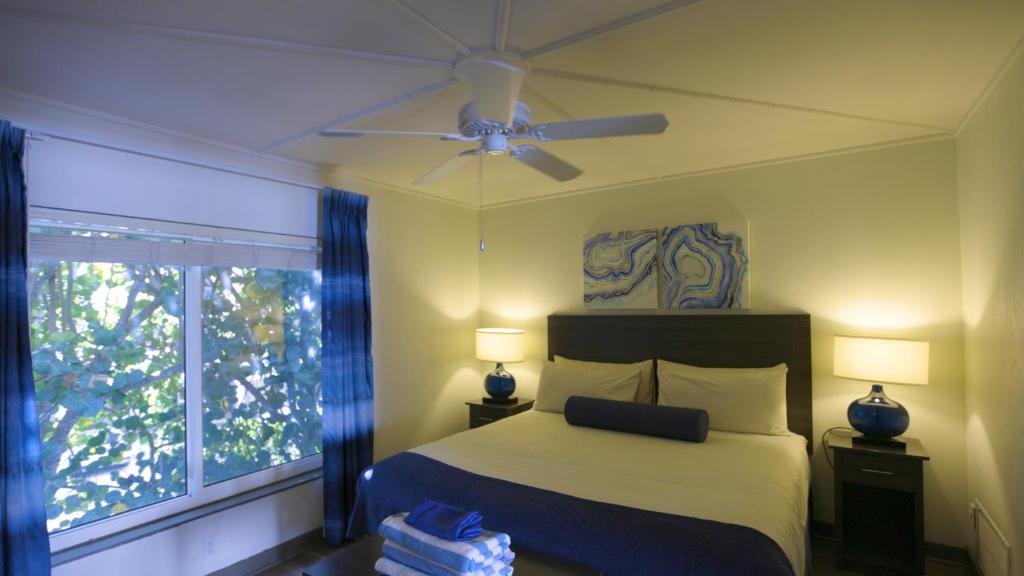 a bedroom with a bed with a ceiling fan and a window at The Dover House Resort in Delray Beach
