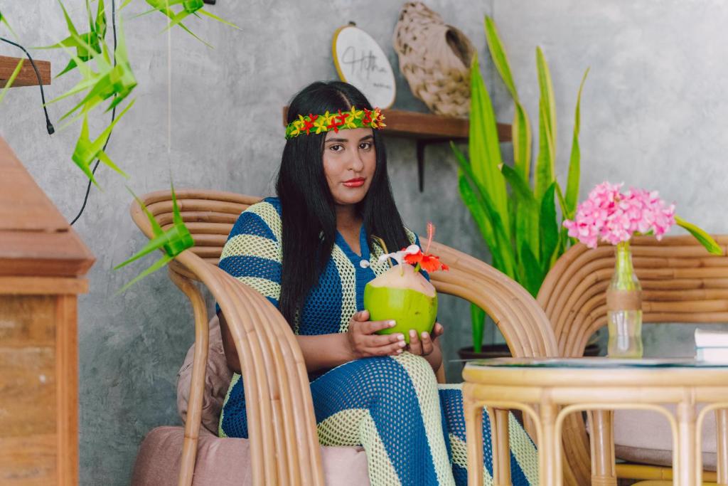 a woman sitting in a chair holding a drink at Hitha Maldives in Omadhoo