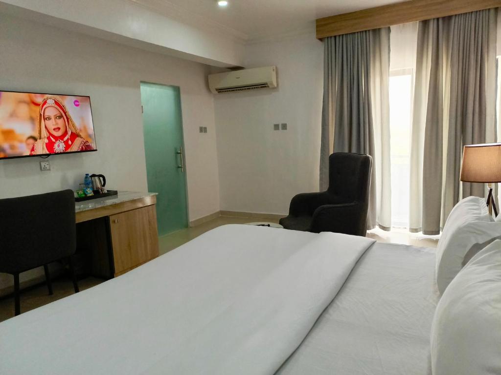 Kakanfo Inn & Conference Centre في إيبادان: غرفة في الفندق بها سرير وتلفزيون على الحائط