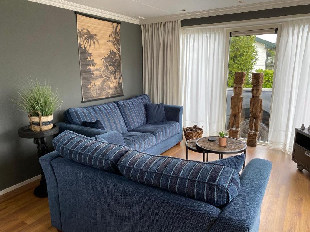 een woonkamer met een blauwe bank en een tafel bij Chalet Maiva - De Krabbenkreek in Sint Annaland