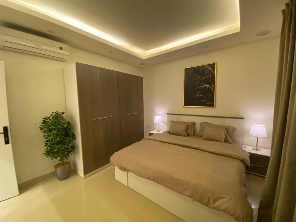 a bedroom with a bed with two lamps and a plant at شقق ارفلون دخـول ذاتي in Riyadh