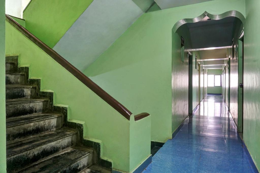 una escalera en un edificio con una pared verde y escaleras en OYO Savanna Garden Lodge en Pune