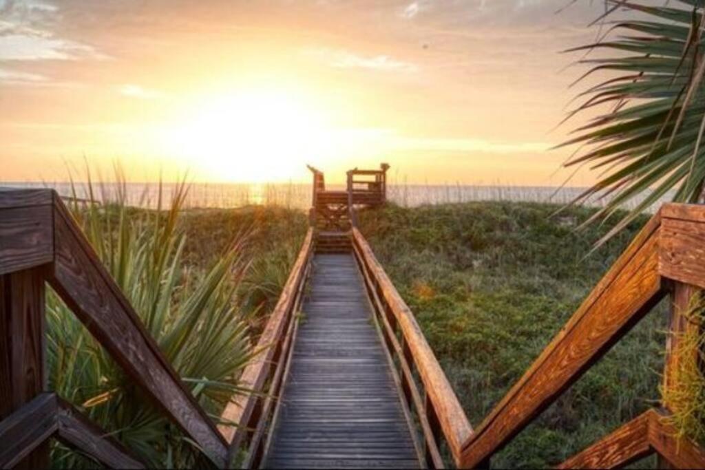 een houten promenade die bij zonsondergang naar het strand leidt bij Pelican Inlet-Cozy Beach Condo! in St. Augustine