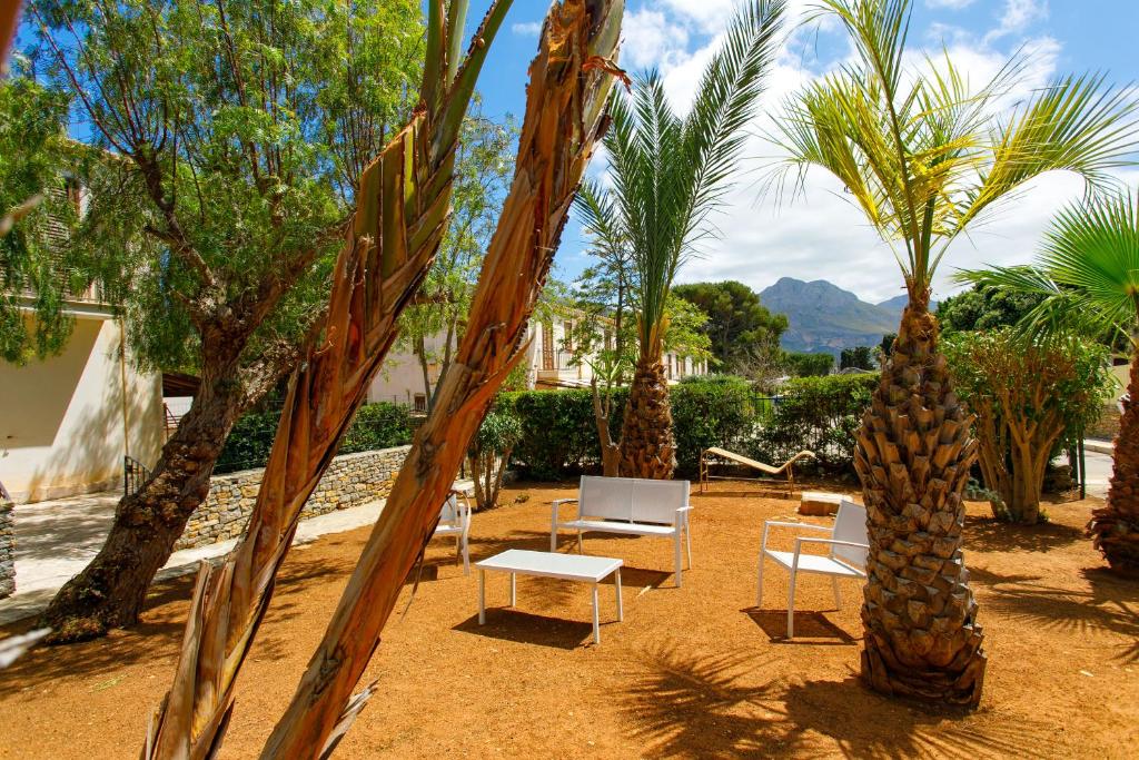 a resort yard with palm trees and chairs and tables at SanVitoTour- Residence Il Baglio in San Vito lo Capo