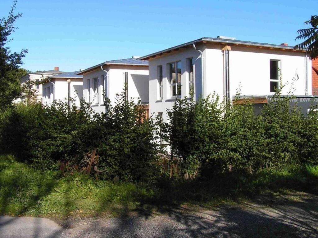 uma casa branca com arbustos à frente em Luxury holiday home with sauna em Heiligendamm