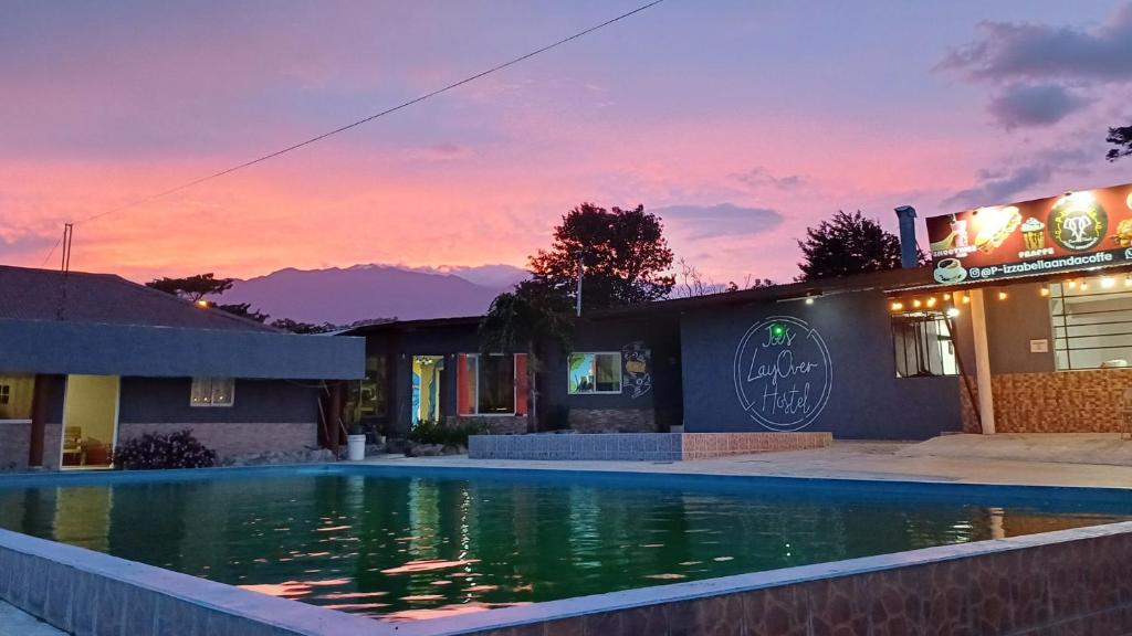 una piscina frente a un edificio con puesta de sol en Joe's Layover Hostel Boquete en Boquete