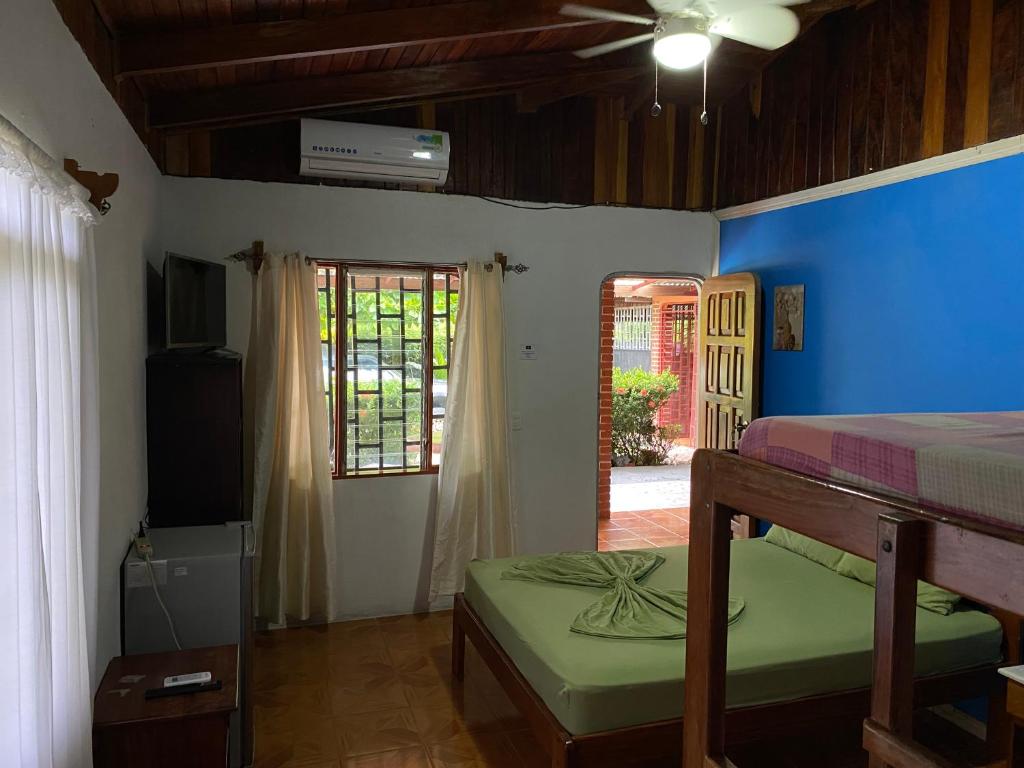 1 dormitorio con 1 cama, TV y ventana en Corcovado Hostel, en Puerto Jiménez