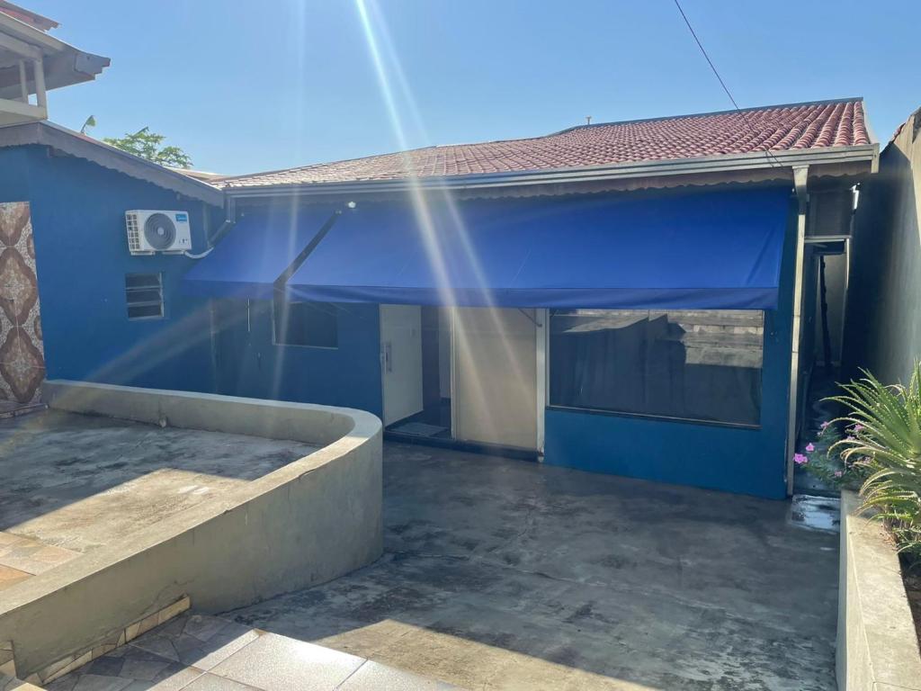 una casa con un garaje azul con el sol brillando en Pousada Aeroporto Viracopos Campinas, en Viracopos