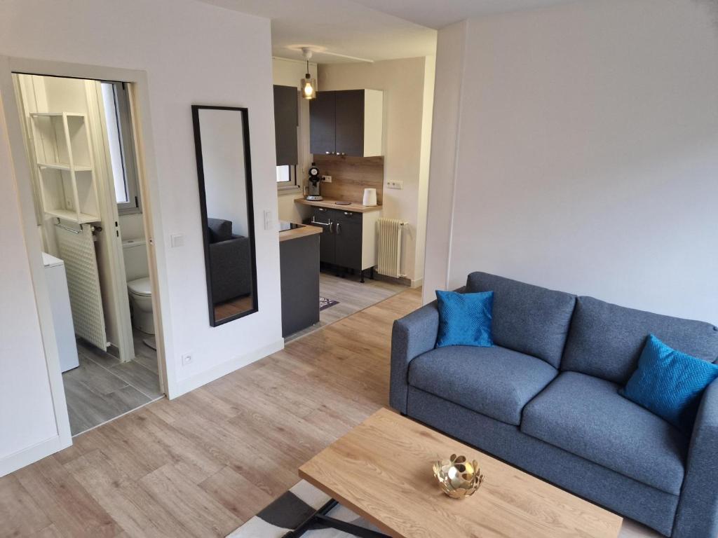 ein Wohnzimmer mit einem blauen Sofa und einem Tisch in der Unterkunft Appartement traversant ensoleillé in Boulogne-Billancourt