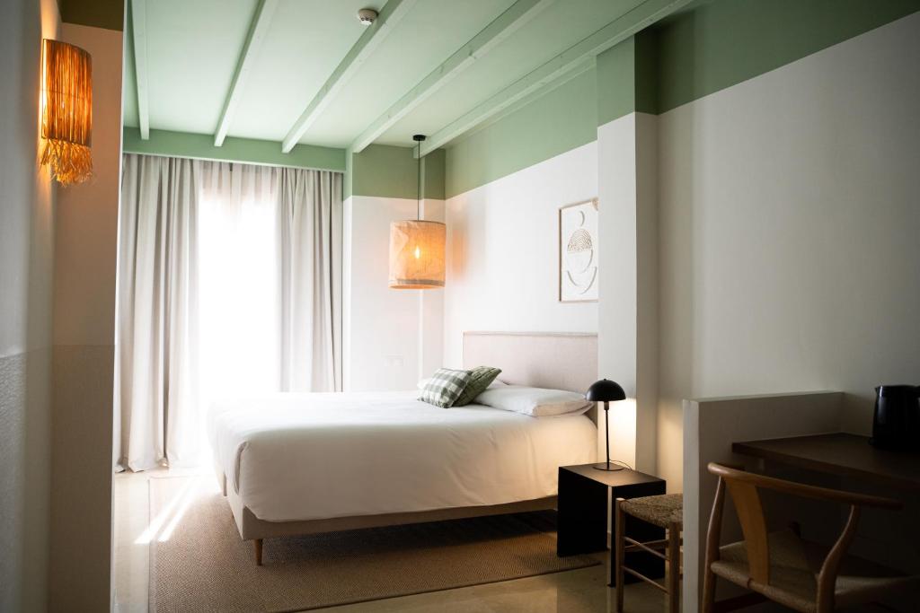 1 dormitorio con cama blanca y ventana en Rooms by JovA, en El Campello