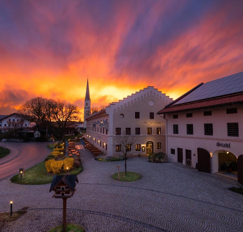 a sunset over a town with a church in the background at LANDHOTEL ALTE ZOLLSTATION- Historical Building in Pittenhart