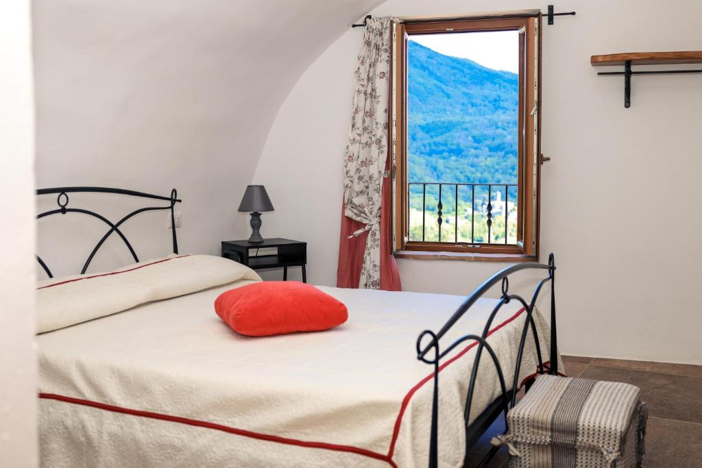 1 dormitorio con cama con almohada roja y ventana en Ca'Toni en Bagnone