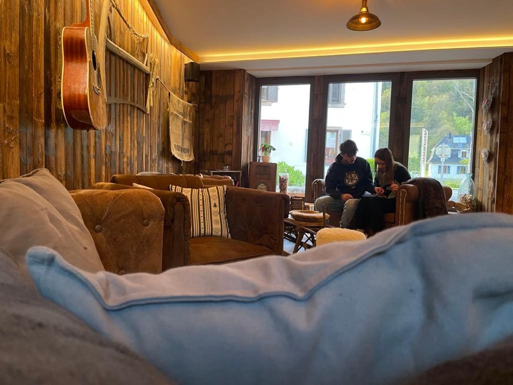Dos personas sentadas en una sala de estar mirando por la ventana en Hôtel Restaurant Valneige, en Mittlach