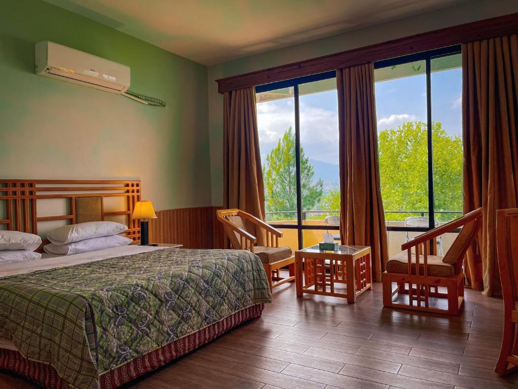a hotel room with a bed and a large window at Rock City Resort in Swat