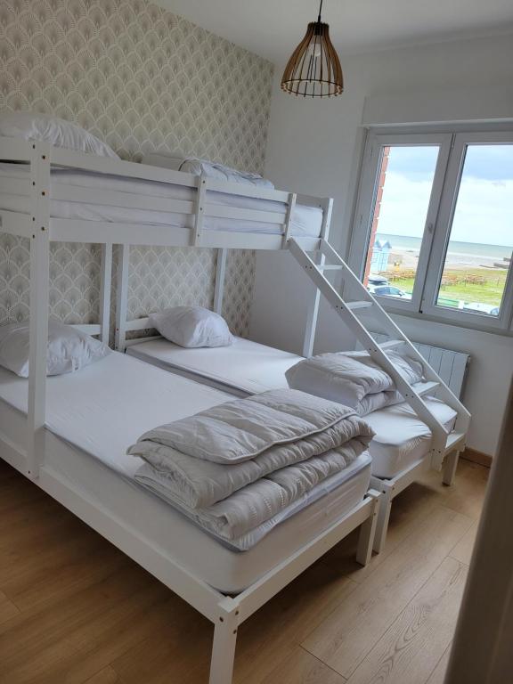 dwa łóżka piętrowe w pokoju z oknem w obiekcie Le Solemare Appartement T3 Face Mer Cayeux sur Mer w mieście Cayeux-sur-Mer