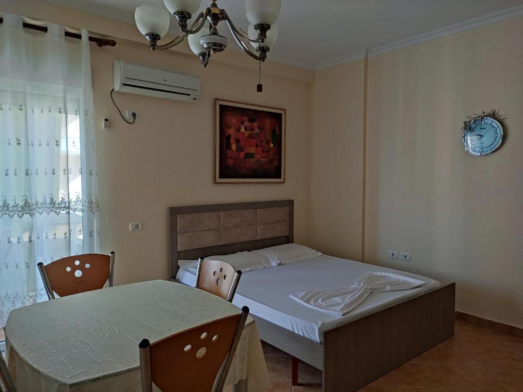 a bedroom with a bed and a table and a clock at Apartment in Lungo Mare Vlore in Vlorë