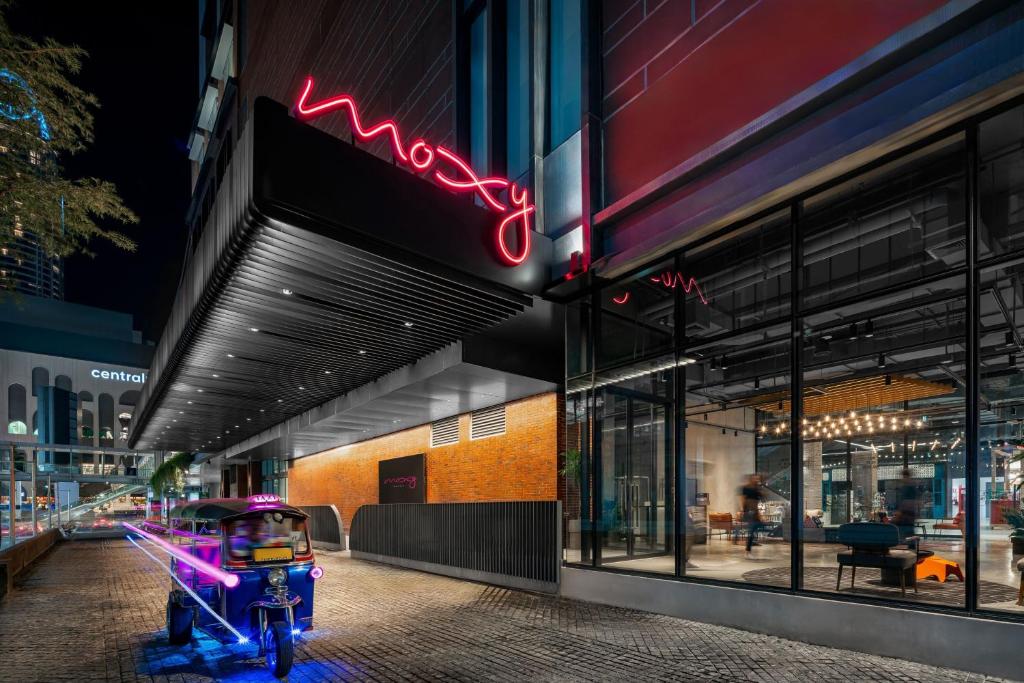 una persona conduciendo una motocicleta delante de una tienda en Moxy Bangkok Ratchaprasong, en Bangkok