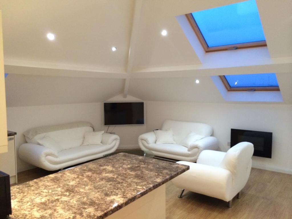 a living room with two white chairs and a flat screen tv at Grosvenor house in Cardiff