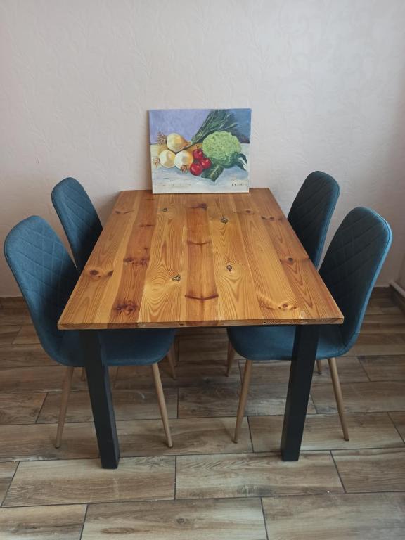 a wooden table with blue chairs and a painting on it at Apartament Parkowa in Nowy Targ