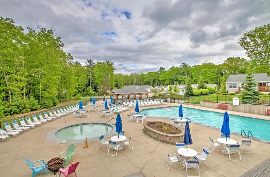 una piscina con sillas, mesas y sombrillas azules en Wells Cottage with Resort Amenities - 1 Mile to Beach! en Wells