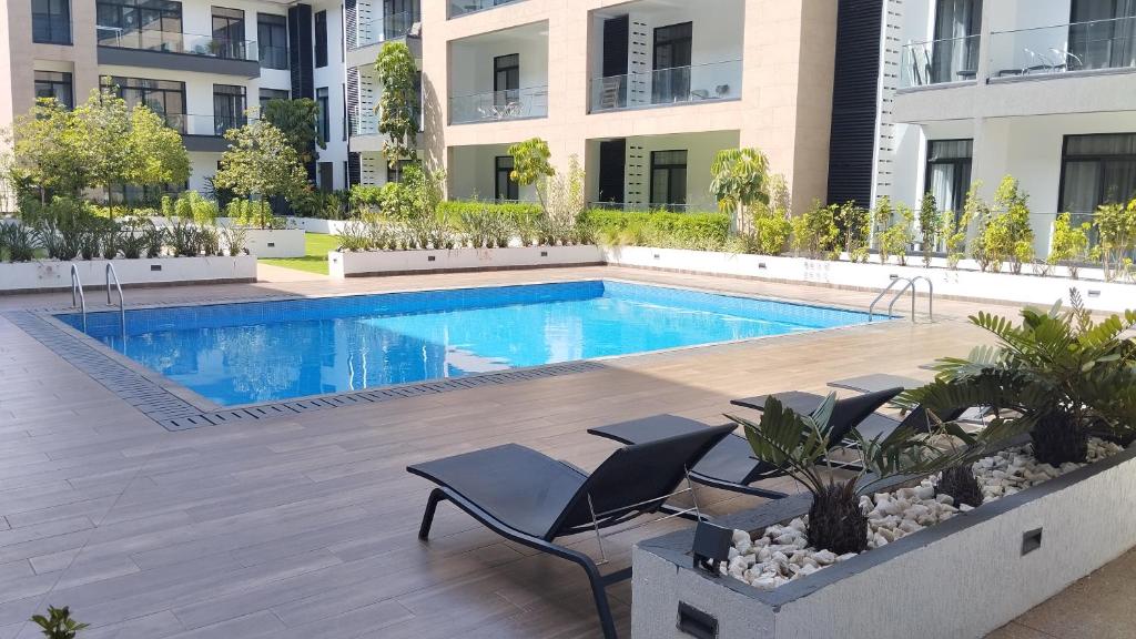 - une piscine avec des chaises à côté d'un bâtiment dans l'établissement Golden Place Properties At The Embassy Gardens, à Accra
