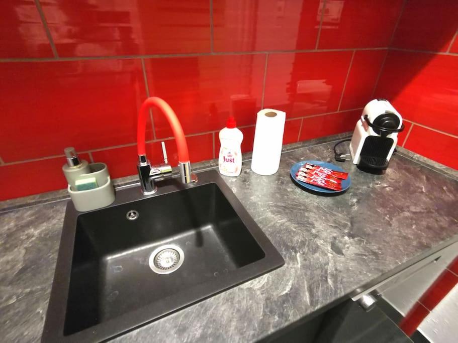 - un comptoir de cuisine avec un évier et un mur rouge dans l'établissement H&A Suite Newly City Center 2 Bed & convenient, à Budapest