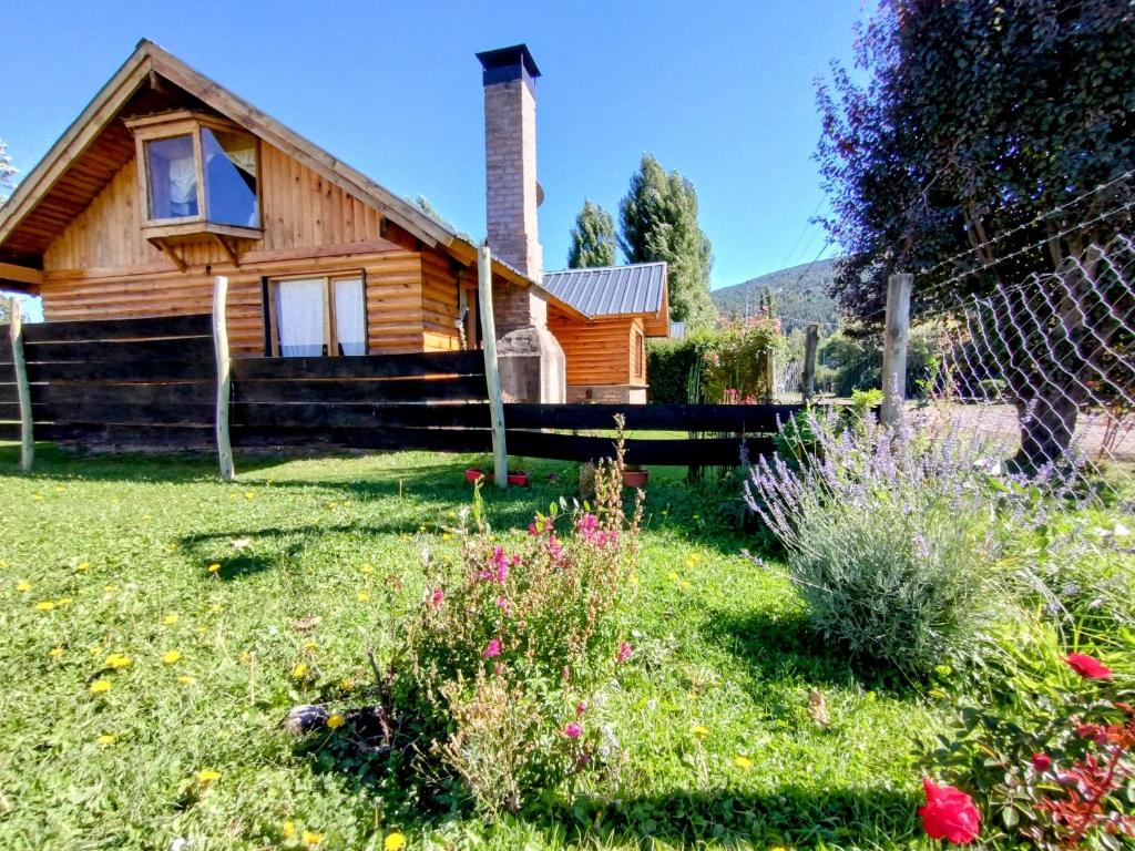 una casa de madera con un patio con flores en Cabaña los teros en San Martín de los Andes