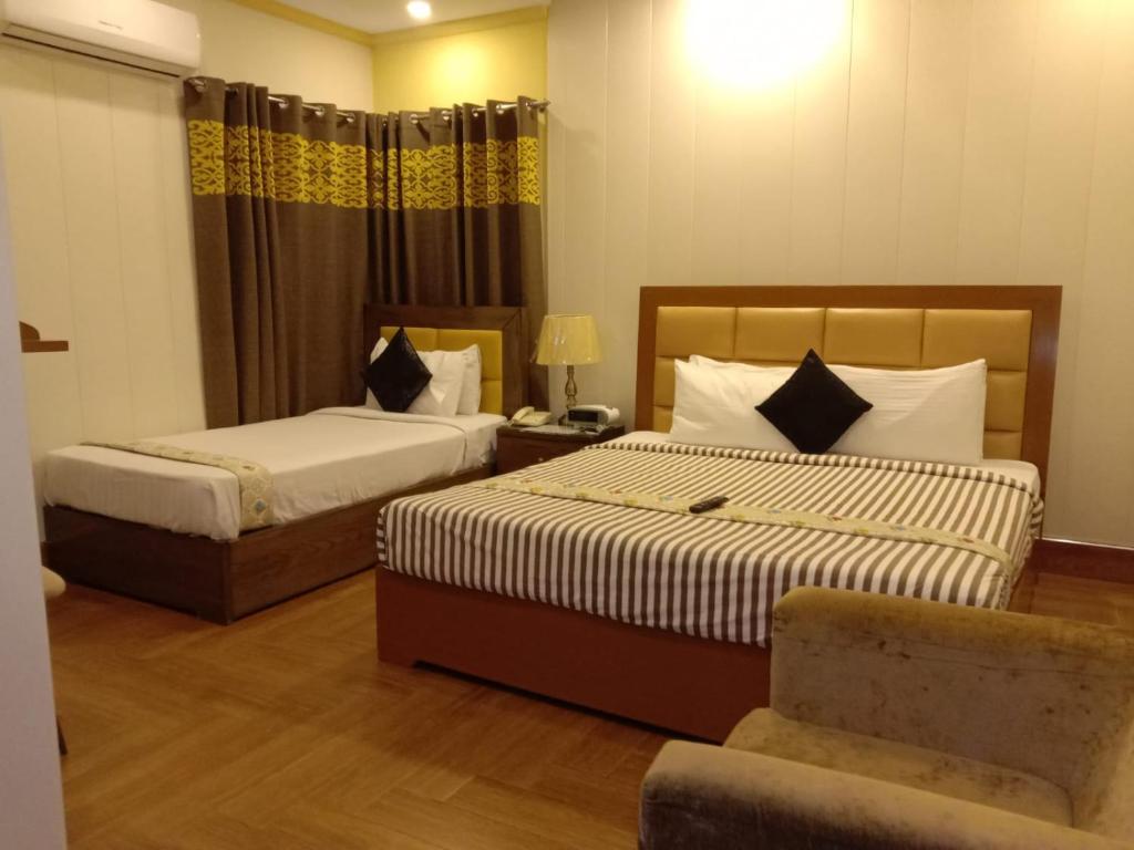 EXPRESS HOTEL في لاهور: غرفة فندقية بسريرين وكرسي