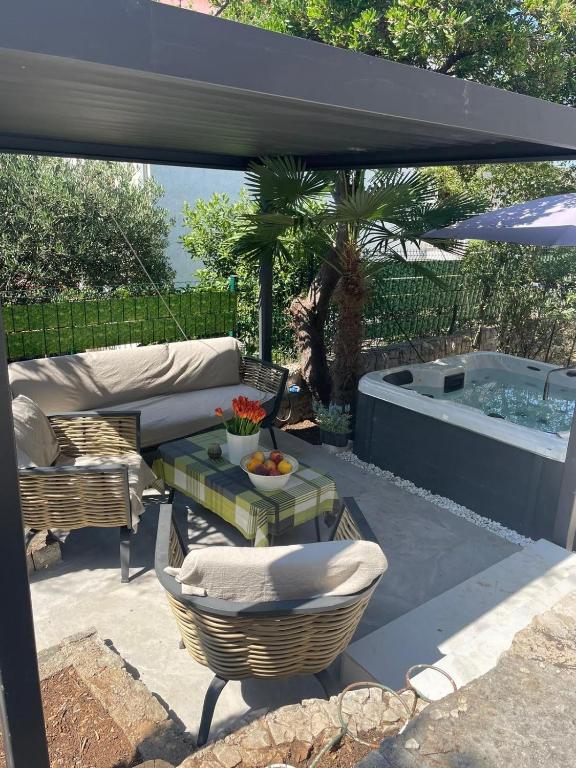 a patio with a hot tub and a table and chairs at Libra in Okrug Gornji