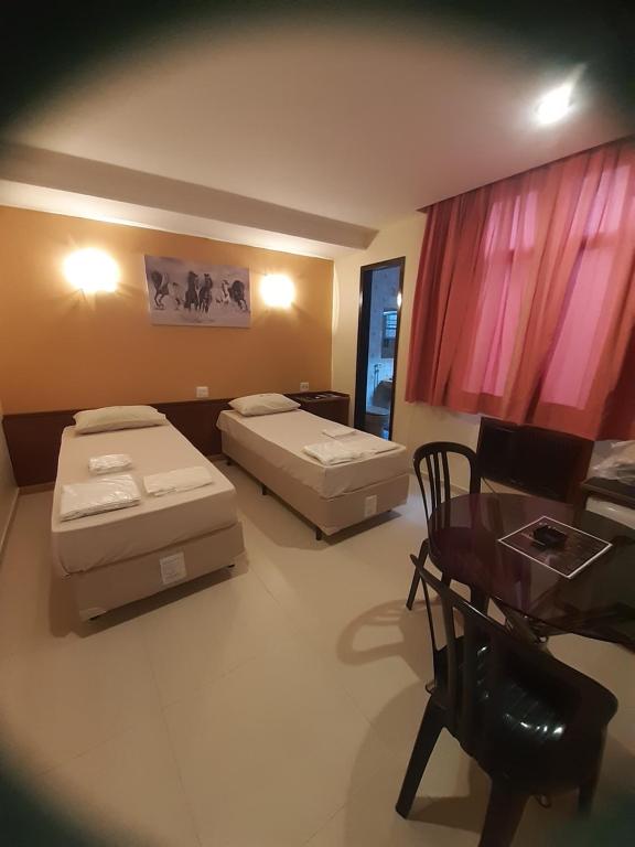 a room with two beds and a desk and a table at Hotel Paraguai (Adult Only) in Rio de Janeiro