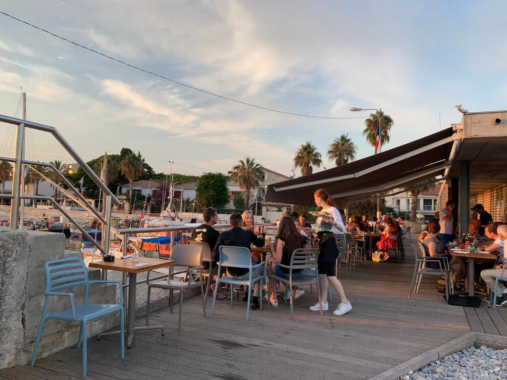 a group of people sitting at tables on a deck at Sea view front beach apartment deluxe near Nice airport in Cagnes-sur-Mer
