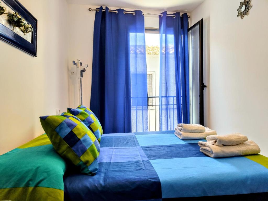 1 dormitorio con cama azul y ventana en El Balcón de Zuheros, en Zuheros