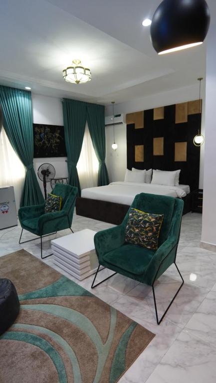 um quarto com uma cama e 2 cadeiras verdes em SHORTLETMART Apartments em Lekki