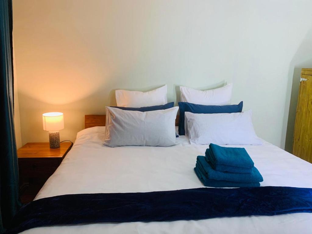 un letto bianco con lenzuola e cuscini blu di Afrikawisa@Rosebank a Johannesburg