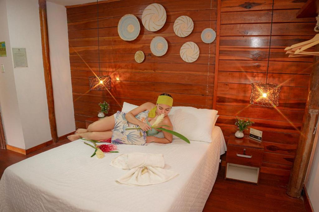 a woman laying on a bed in a room at Ecohotel Yachay Tayrona in El Zaino