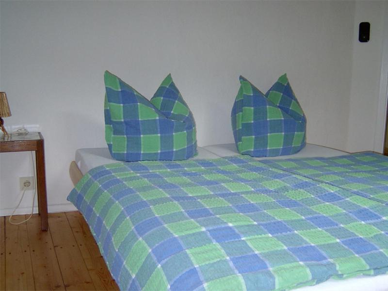 Bett mit blauer und grüner Bettwäsche und Kissen in der Unterkunft Waldhaus in Wernigerode